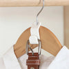 A close-up of a white hanger with a metal hook connector attached to a brown leather strap.