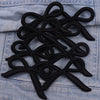 Black felt bow embroidery iron-on patches arranged on a denim fabric surface.
