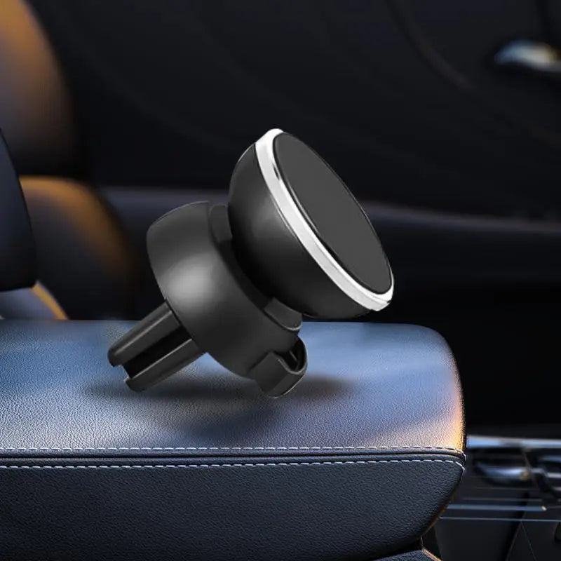 Support de téléphone magnétique noir posé sur un siège de voiture en cuir foncé.