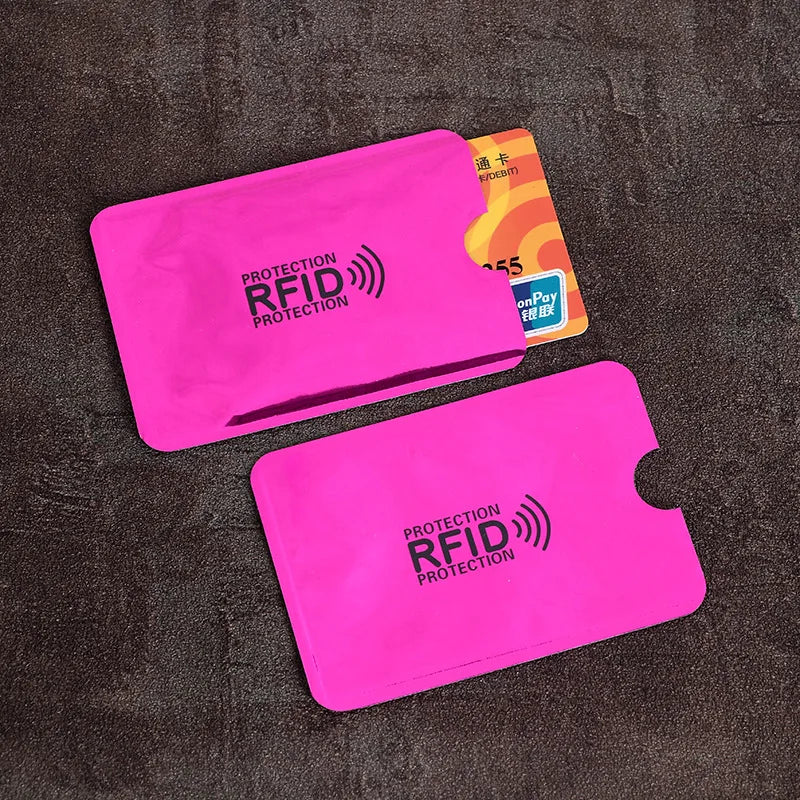A set of pink RFID protection card sleeves and a yellow card are displayed on a dark surface.