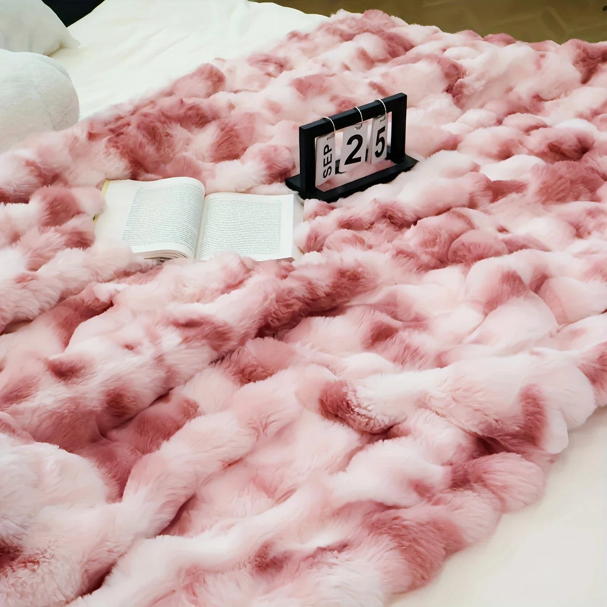 Pinkes Kunstfell-Kaninchen-Fleece-Decke liegt auf einer weißen Fläche mit einem schwarzen Marker, der den 25. September anzei