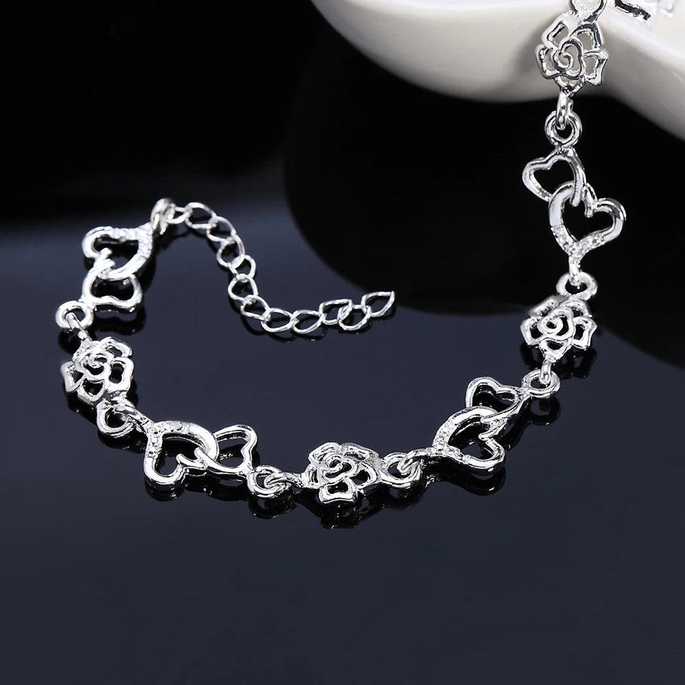 Zartes Sterling-Silber-Armband mit miteinander verbundenen Herzen- und Blumen-Charms.