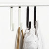 A set of four black and white over-the-door hooks with soft rubber coating hanging on a white surface.