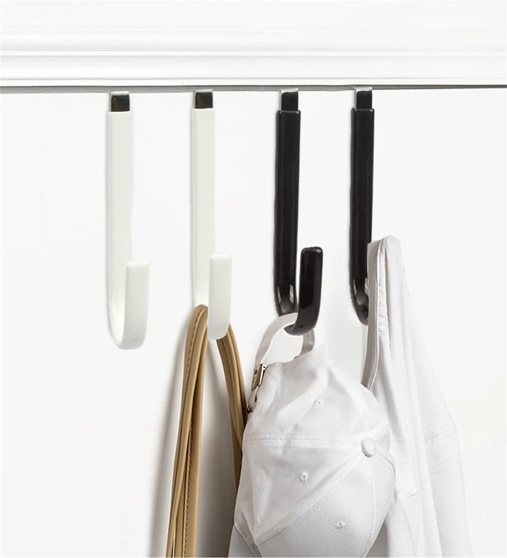 A set of four black and white over-the-door hooks with soft rubber coating hanging on a white surface.