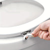 A hand is lifting the toilet seat using a touch-free lifter mechanism on a white toilet.