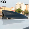 A black shark fin car antenna mounted on a white vehicle's roof.