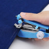 A hand is operating a small blue portable handheld sewing machine on a dark blue fabric.