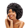 A woman wearing a black satin sleeping bonnet tied in a bow, looking at the camera.