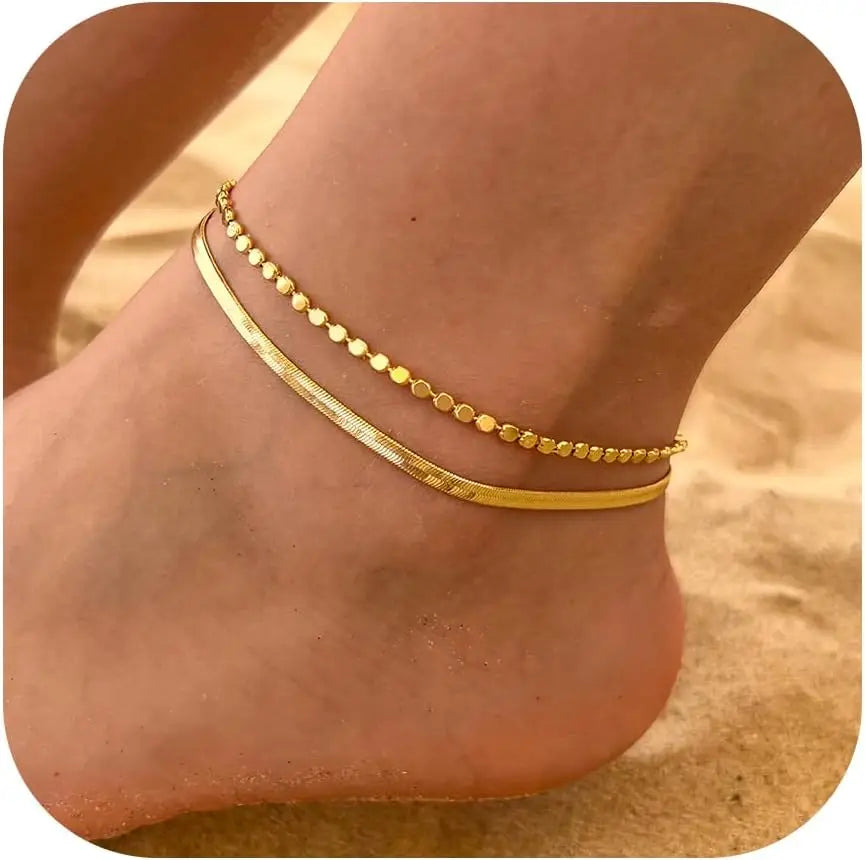 A gold layered herringbone anklet set worn on a person's ankle.