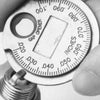 Close-up photo of a coin-type spark plug gap gauge showing measurements on the dial.