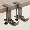 A close-up view of a metallic desk hook designed to hold bags and coats, mounted on a wooden surface.