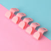 A row of pink space-saving cascading hanger connector hooks arranged diagonally on a pink and blue background.