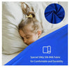 A child is resting on a bed with a blue fabric and a dark blue circular swatch of silk fabric.