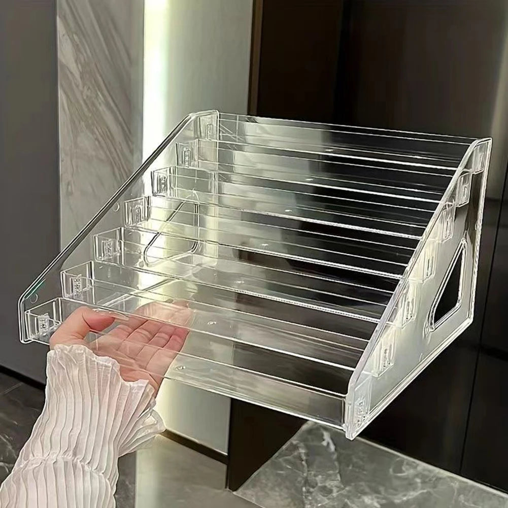 A hand holds an acrylic ladder display stand with multiple clear compartments.
