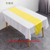 A white tablecloth with a yellow satin table runner is displayed on a table.