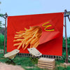 Grande bannière rouge avec un graphique de frites, installée à l'extérieur avec une table et des chaises.