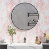 A bathroom vanity featuring a round mirror with black frame, marble countertop, and toiletries.