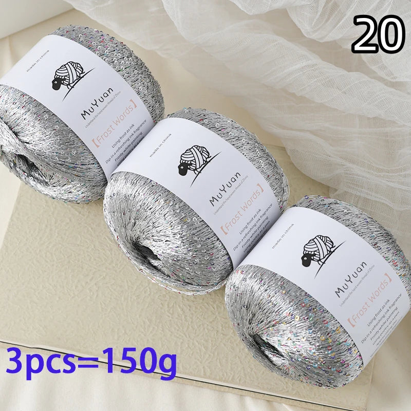 A pile of 20 spools of silver glitter yarn is displayed on a light surface.