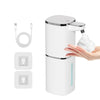 A white touchless infrared smart soap dispenser with a pump head and USB charging cable is shown being used by a hand.