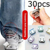 A hand holds several clear and translucent invisible hem shortening clips for trousers