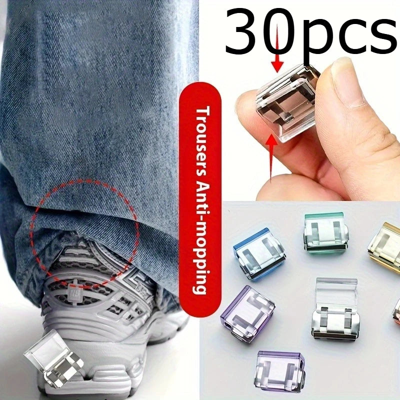 A hand holds several clear and translucent invisible hem shortening clips for trousers