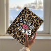 A leopard print tri-fold iPad case with the word BURN on the front is held up against a window background.