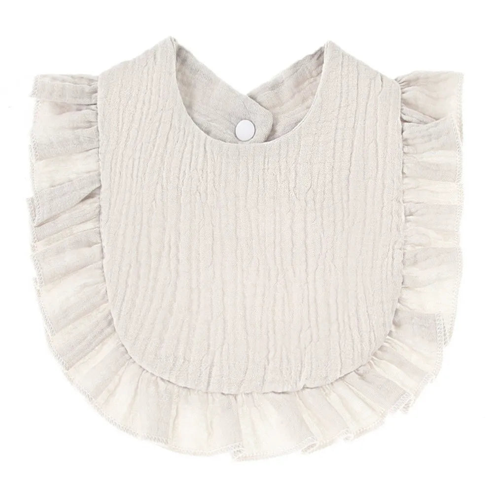 A light beige soft cotton baby bib in a bandana style with ruffled edges.