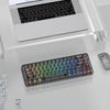 A close-up view of a black mechanical keyboard with crystal clear RGB backlit keycaps resting on a white desk.