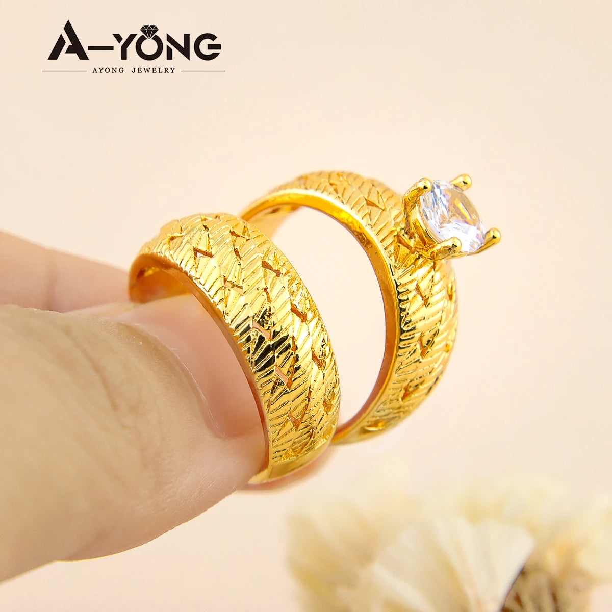 A pair of elegant gold-plated zirconia stackable rings are shown being held by a hand against a light background.