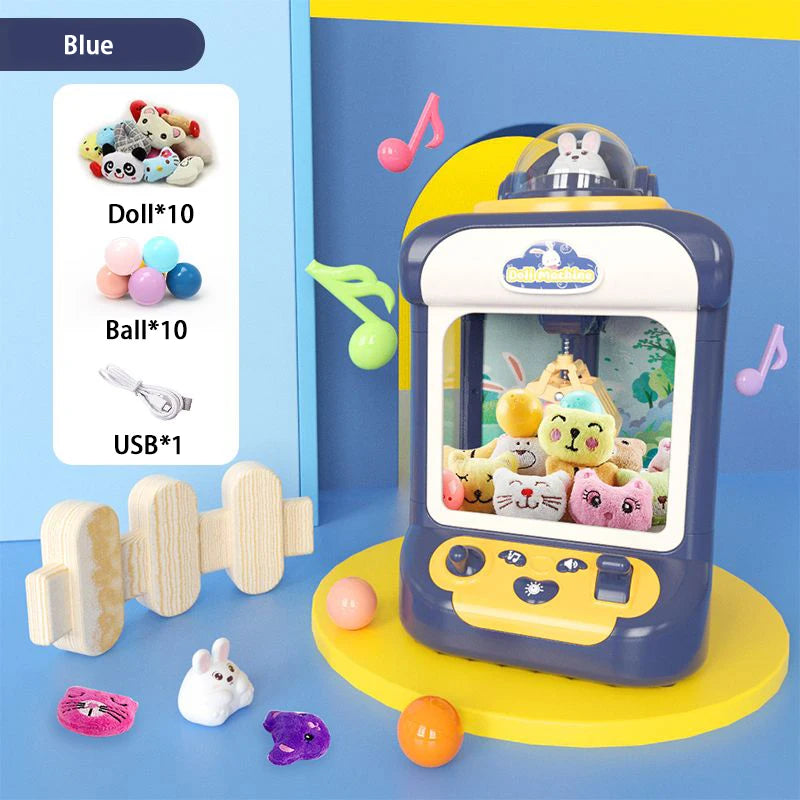 A blue mini claw crane machine for kids with lights and music is displayed on a yellow stand next to various toys.