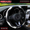 Black steering wheel with white and blue accents and a carbon fiber cover installed in a car interior.