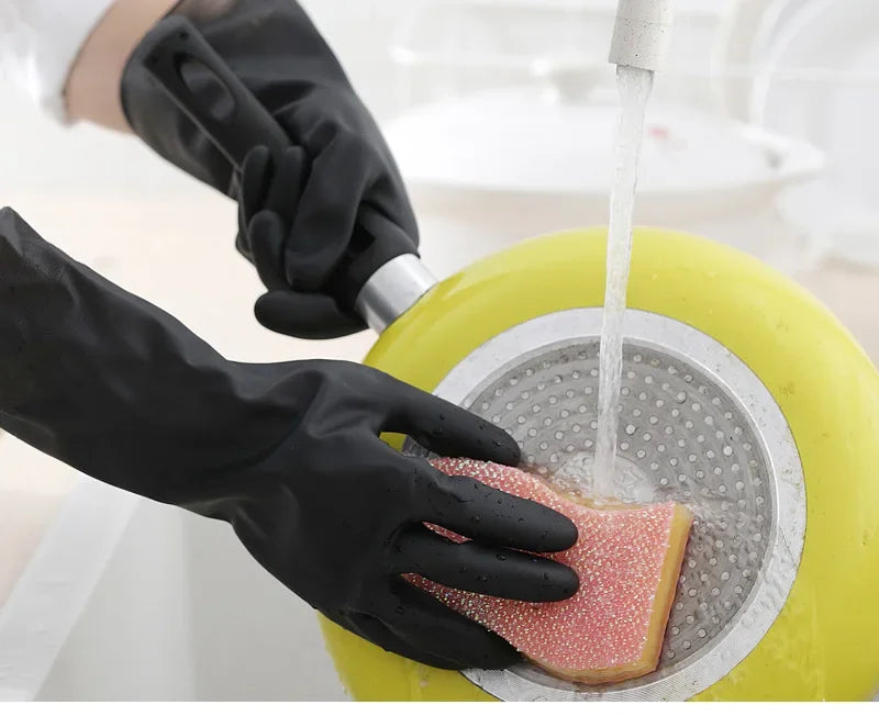 A hand wearing a black rubber cleaning glove is using it to pour water over a piece of food in a yellow container.