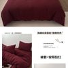 Ein Set aus tiefmaroonfarbenen, faltigen Bettbezügen und Kissen auf einem Bett.