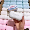 A hand holds a white stress relief squishy soap shape fidget toy in various colors and packaging.