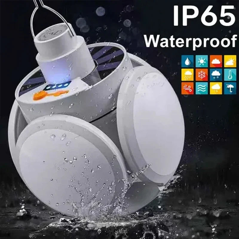 A white foldable solar camping lantern is shown with water splashing around, highlighting its waterproof IP65 rating.