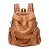 A tan leather backpack featuring rivets and straps, shown from the back.