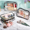 A clear PVC travel makeup and toiletry organizer bag with a zipper, showing various cosmetic products and brushes.