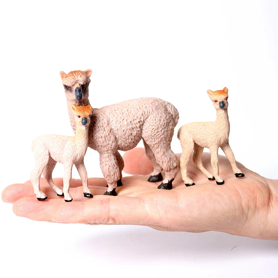 Three realistic animal figurines of deer or fawn in natural tones resting on a human palm.