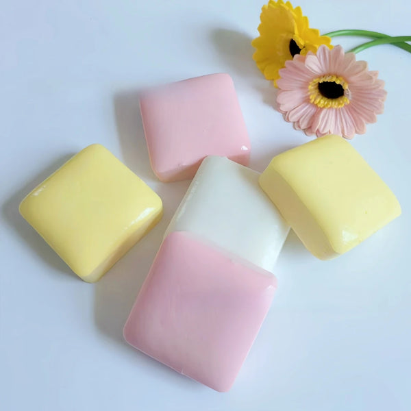 A collection of pink and yellow squishy toys shaped like cakes, with a yellow square and a larger pink cake.