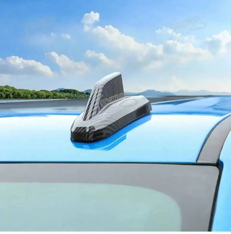 Chrome-style car antenna cover trim installed on a vehicle roof against a blue sky backdrop.