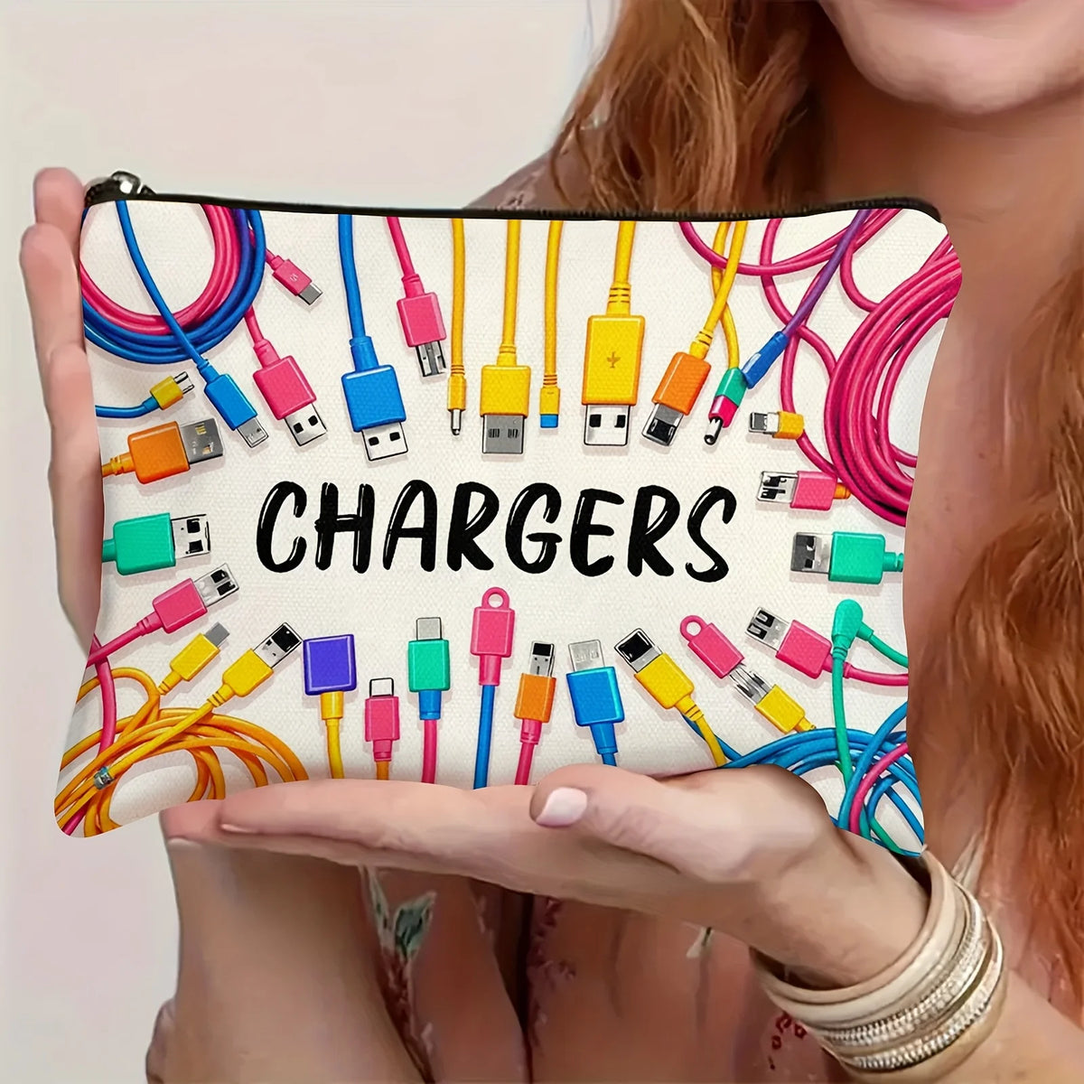 A hand holds a pouch filled with various colorful charging cables and power adapters.