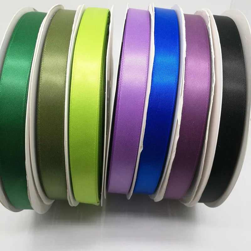 A collection of double face satin ribbons in various solid colors, including green, olive, lime, purple, blue, and black.
