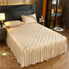 A beige quilted bed skirt with vertical pleats is displayed on a bed in a modern bedroom setting.