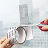 A hand is unwrapping a roll of white self-adhesive window screen repair tape, showing the adhesive strip.