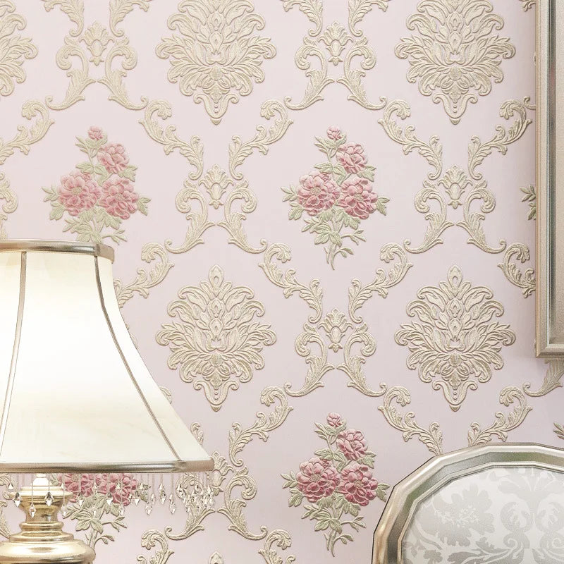 Close-up of pink and cream floral wallpaper featuring ornate scrollwork patterns on a wall.