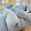 A light blue velvet bedding set featuring a duvet cover and pillows on a bed.
