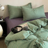 A green and white striped duvet cover set with matching pillowcases on a bed.