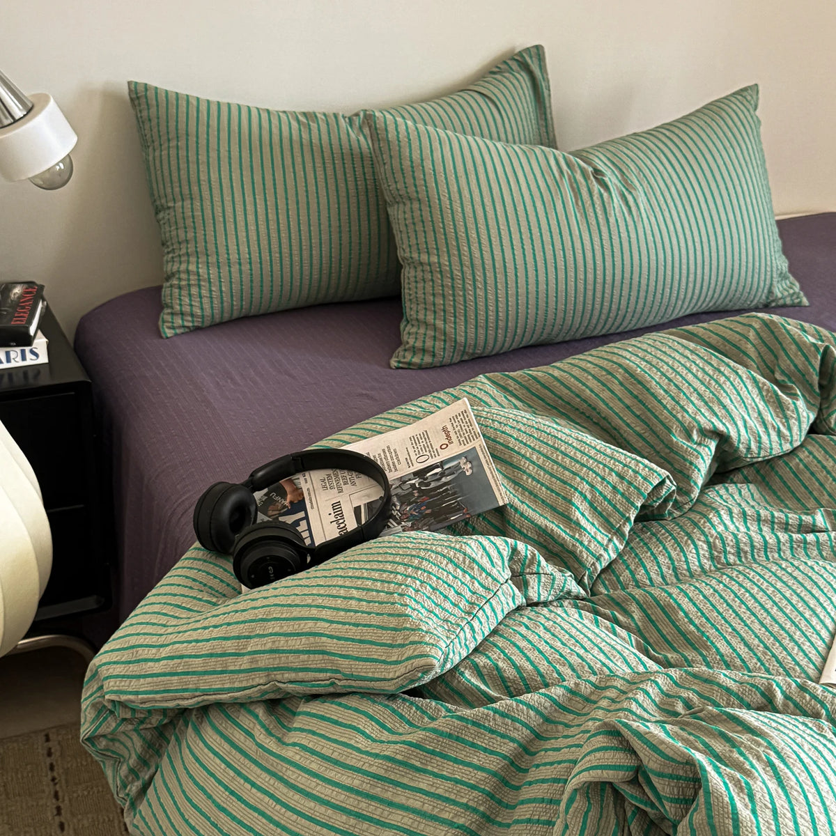 A green and white striped duvet cover set with matching pillowcases on a bed.