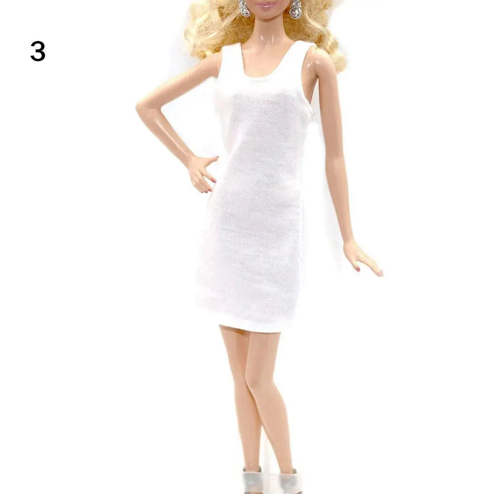 A fashion doll wearing a white, sleeveless mini dress and gold earrings.