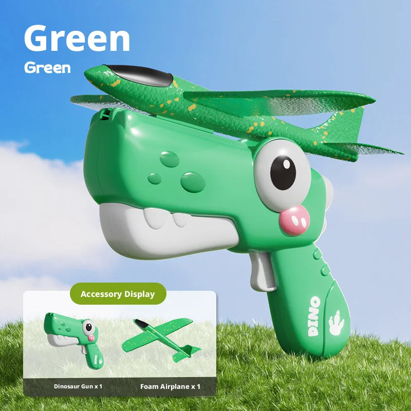 A green dinosaur foam airplane launcher toy set with a large eye and mouth visible against a grassy background.